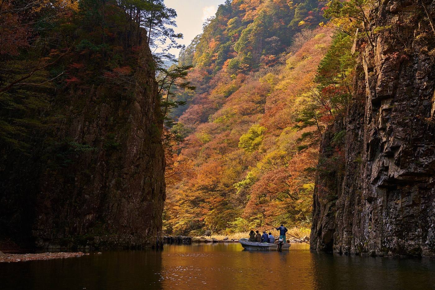 a boat on the river between the cliffs of Sandankyo gorge
