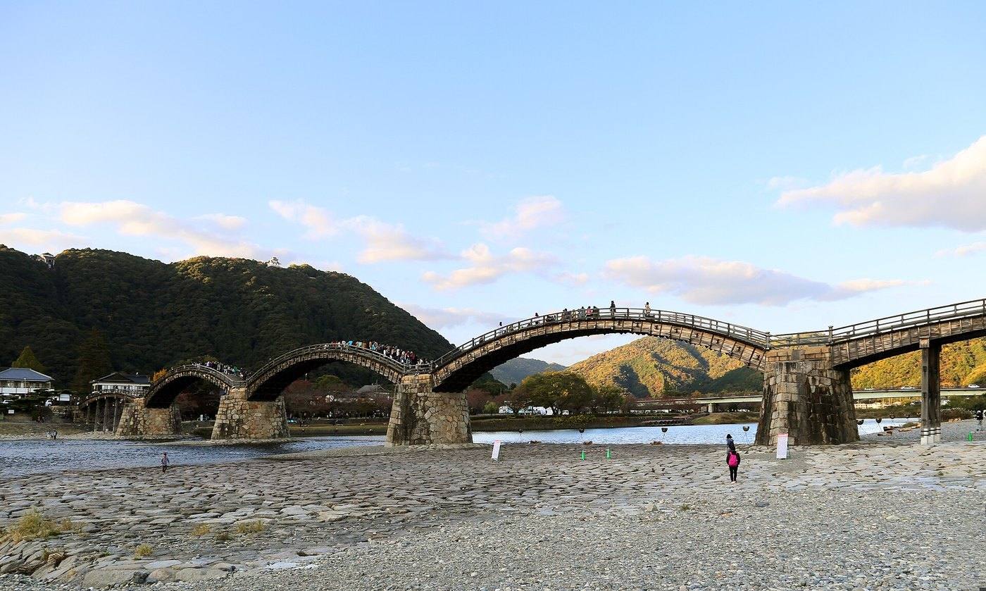 a wooden arched bridge over a river